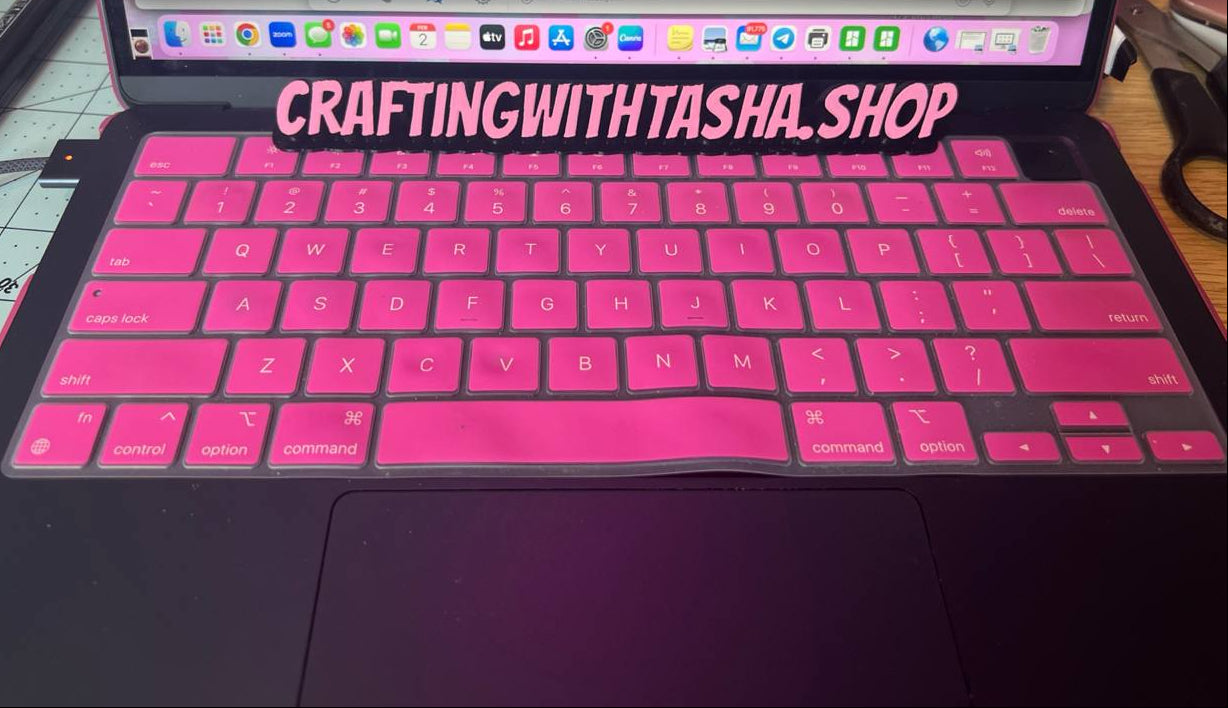 Laptop with pink keyboard cover displaying 'CraftingwithTasha Shop' on a desk.