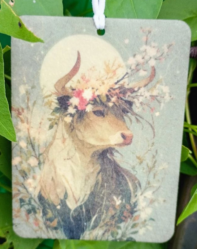 Decorative air freshener with a deer design hanging among green leaves.