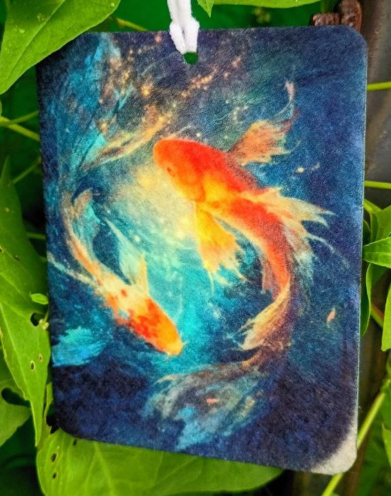 Decorative tag with a goldfish design hanging among green leaves