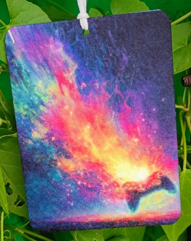 Colorful nebula design air freshener hanging among green leaves