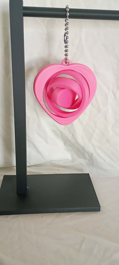 Pink heart-shaped object on a black stand against a white background