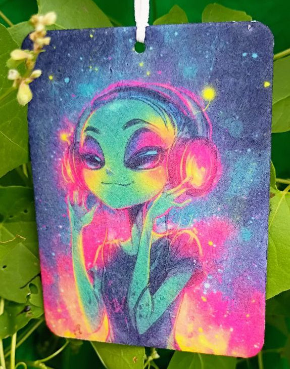Colorful air freshener with a design of a person wearing headphones hanging among green leaves.
