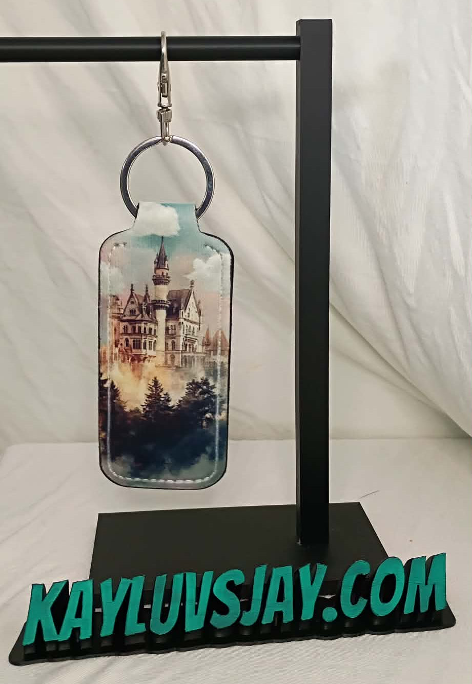 Earring on a stand with a castle design, branded 'KAYLUVSJAY.COM'.