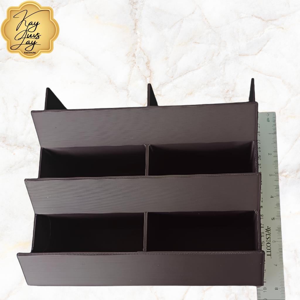 Black organizer with compartments next to a ruler on a light marble background