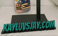 Keychain with dragon design on a stand with 'KAYLUVSJAY.COM' branding.